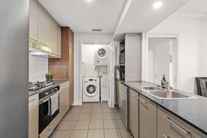 Uma cozinha compacta com fogão, pia e máquina de lavar e secar embutidas.