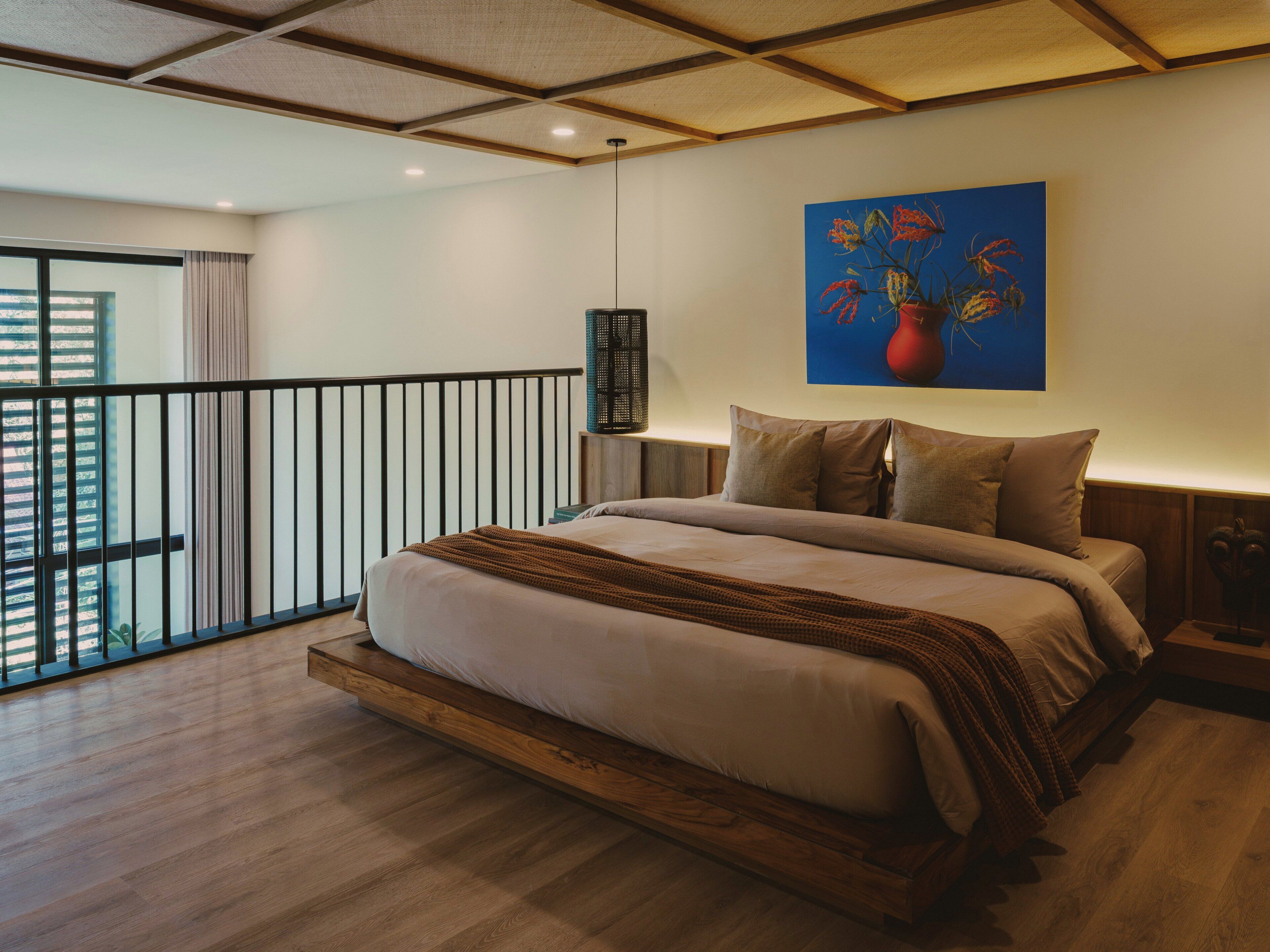 A bedroom with a large bed, a view of the city, and a painting on the wall.