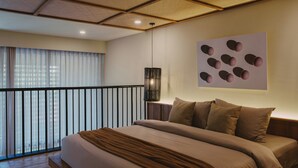 Ein modernes Hotelzimmer mit einem großen Bett, Blick durch einen Balkon und einem Wandbild.