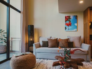 A modern living room with a sofa, ottoman, and a tall floor lamp. - Anandaya Sanur  (Sanur Kauh)
