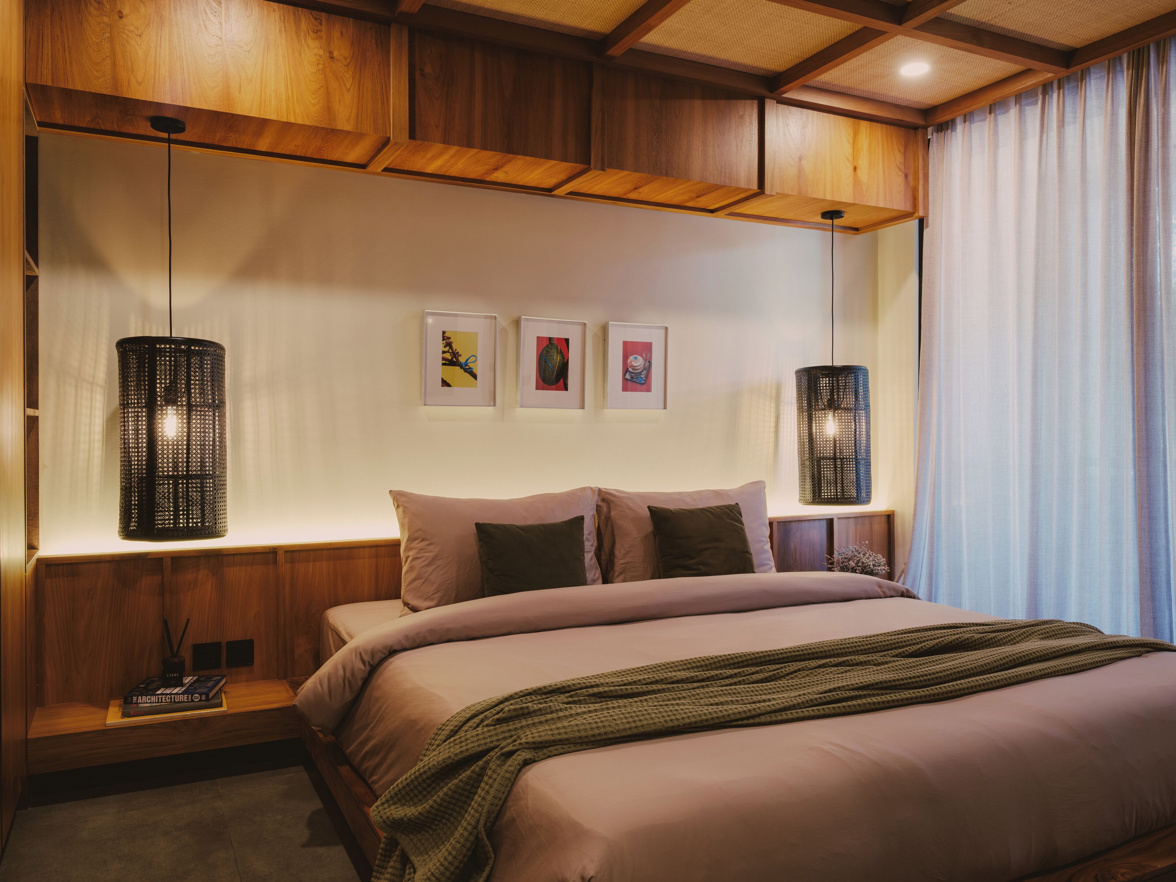A bedroom with a bed, two wall-mounted lamps, and three framed pictures on the wall.