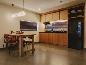 Uma cozinha moderna com armários de madeira, uma geladeira preta e uma mesa de jantar com cadeiras.