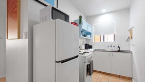 A modern kitchen with white cabinetry, a built-in oven, a microwave, and a sink. - New Farm Nest! 2bed/1bath/2car/balcony (Brisbane)
