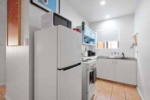 Eine moderne Küche mit weißen Schränken, einem eingebauten Backofen, einer Mikrowelle und einem Spülbecken.