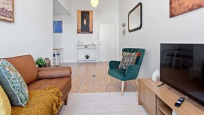 A living room with a sofa, a green armchair, a TV, and a white door in the background. - New Farm Nest! 2bed/1bath/2car/balcony (Brisbane)