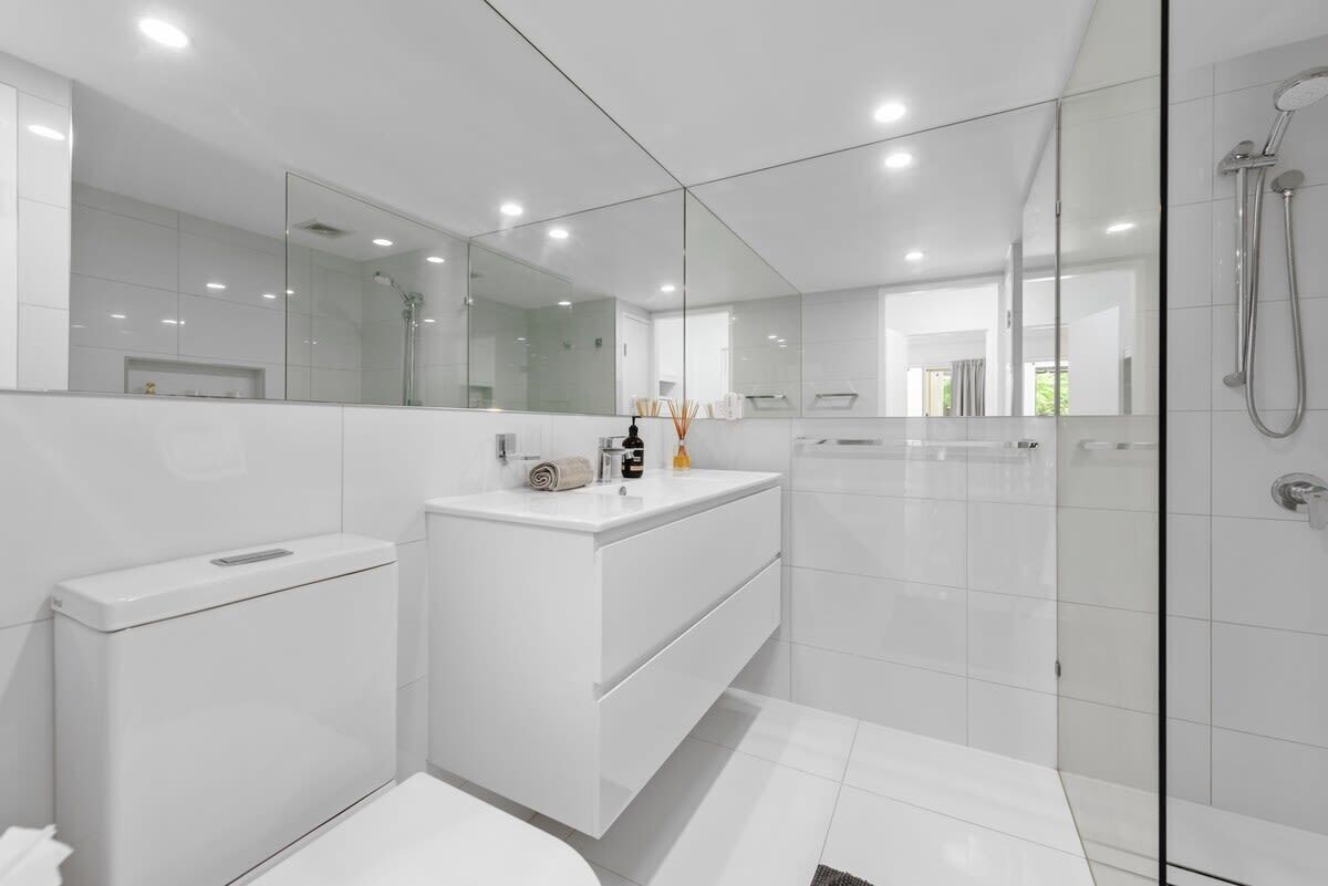 Une salle de bain moderne avec une douche à parois de verre, un meuble-lavabo blanc et un grand miroir.