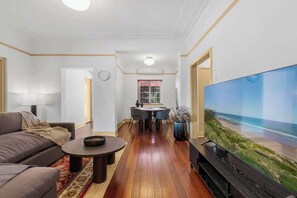 Ein Wohnzimmer mit einer Couch, einem Couchtisch, einem Fernseher und einem Essbereich mit Stühlen und einem Tisch.