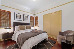 Ein Schlafzimmer mit Bett, Nachttischen, einem Kleiderschrank und einem Sessel.