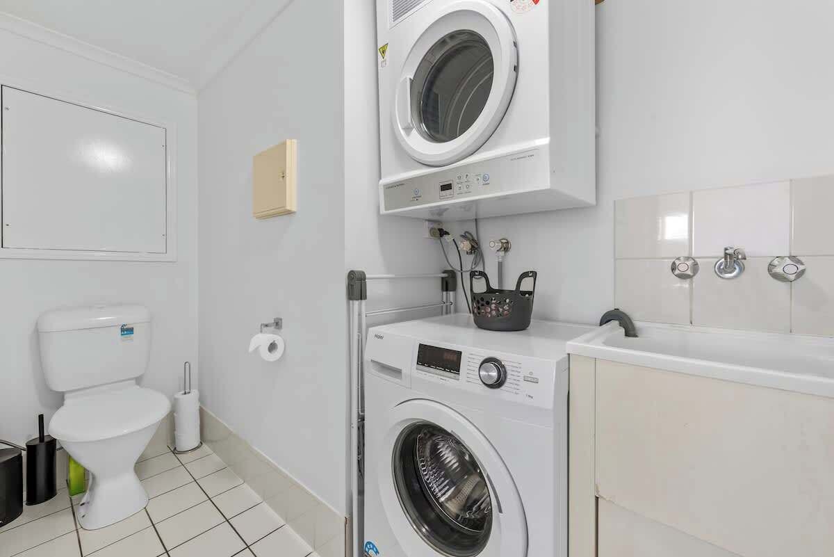 A compact laundry room with a washing machine, dryer, and a small sink.
