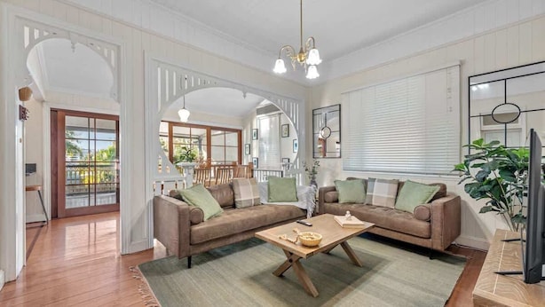 A spacious living room with a large sofa set, a wooden coffee table, and a television. - Comfy Character Qldr ~ 3bed House W/parking (Brisbane)