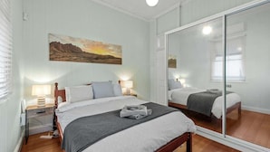 A bedroom with a bed, bedside tables, a mirror, and a painting on the wall. - Comfy Character Qldr ~ 3bed House W/parking (Brisbane)