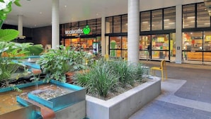 A shopping mall interior with a Woolworths store, indoor plants, and a water feature. - Comfy Character Qldr ~ 3bed House W/parking (Brisbane)