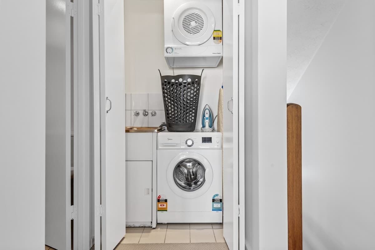 A laundry room with a washing machine, dryer, and ironing board.