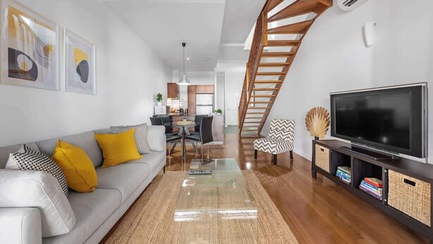 A modern living room with a sofa, TV, and a staircase. - Hipster Loft! ~ 1bed/study/1bath/balconies/1car (Brisbane)
