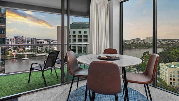 Ein modernes Zimmer mit großem Fenster, einem runden Tisch und vier Stühlen.