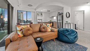 Ein modernes Wohnzimmer mit einem Ecksofa, einem Sitzsack und Blick auf die Stadt.