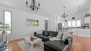 Un salon moderne avec un canapé en cuir noir, une table basse en verre et un lustre.