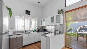 Une cuisine moderne avec des meubles blancs, des appareils en acier inoxydable et un grand îlot central.