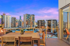 Ein Balkon mit Tisch und Stühlen mit Blick auf eine Skyline mit Hochhäusern.
