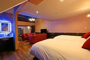 A hotel room with a large bed, a red upholstered chair, a desk with a mirror, and a flat-screen TV. - DAITO ONSEN Hotel The Ocean Hills (Kakegawa)