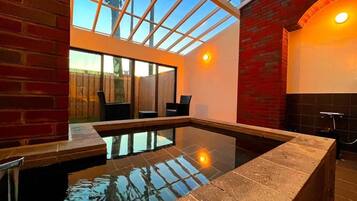 A modern indoor pool with a glass ceiling, brick walls, and a seating area.