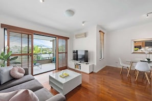 Ein modernes Wohnzimmer mit Sofa, Couchtisch, Fernseher und Essbereich.