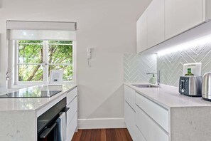 Eine moderne Küche mit Einbauofen, einem Fenster mit Blick ins Grüne, einer Küchenzeile mit Fischgrätenmuster und einer Arbeitsplatte mit Toaster und Wasserkocher.