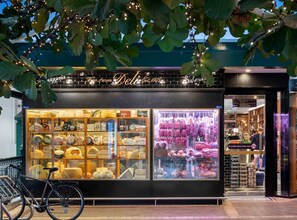 Ein Schaufenster mit Käse und Wurst, ein Fahrrad vor der Tür und ein Schild über dem Eingang.