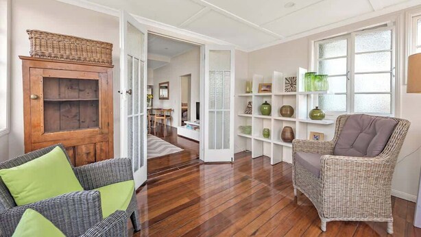 Quarto com cadeira de vime, armário de madeira e estante de livros.