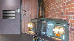 Un coche antiguo estacionado en un garaje con un muro de ladrillo y una puerta de madera.