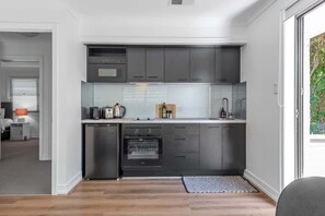 A compact kitchen with modern appliances, a dishwasher, and a built-in oven. - Noble House~2 Bed/1bath/1car~parklands + Transport (Brisbane)