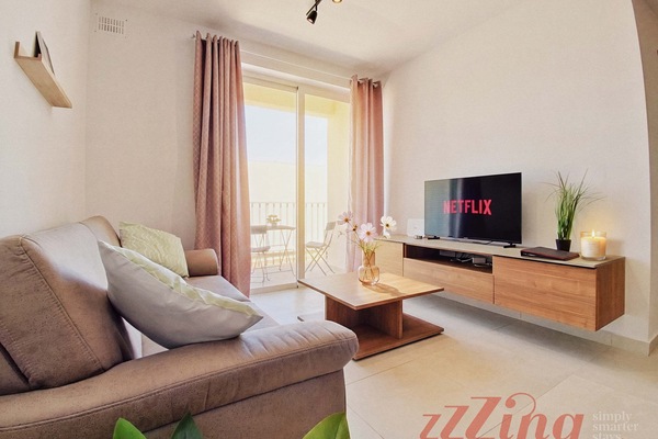Comfortable living room area with smart TV, connected to a balcony overlooking the town.