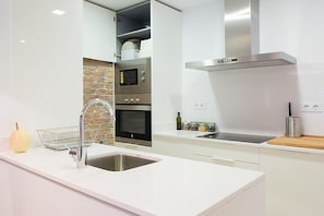 Eine moderne Küche mit Spülbecken aus Edelstahl, Backofen, Mikrowelle und Dunstabzugshaube.