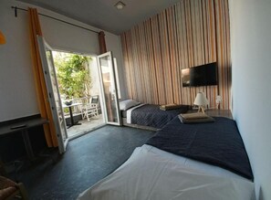 A hotel room with a bed, a TV, a desk, and a sliding door to a balcony. - Gouves Sunset Apts (Kato Gouves)