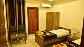 Un dormitorio con cama, mesita de noche, silla, armario y unidad de aire acondicionado.