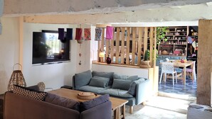En stue med en sofa, et sofabord, et fjernsyn ophængt på væggen og et spiseområde med et bord og stole.