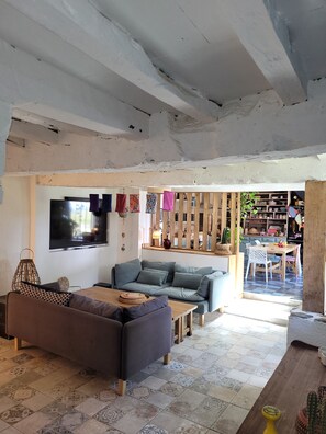 Un salon comprenant un canapé, une table basse, un téléviseur fixé au mur et un coin repas avec une table et des chaises.