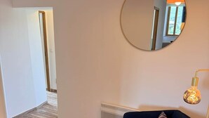 Un salon moderne avec un canapé bleu foncé, un tapis rond, un miroir rond et un lampadaire.