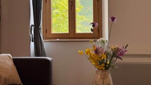 Une pièce avec une fenêtre, un canapé, une table et un vase rempli de fleurs.