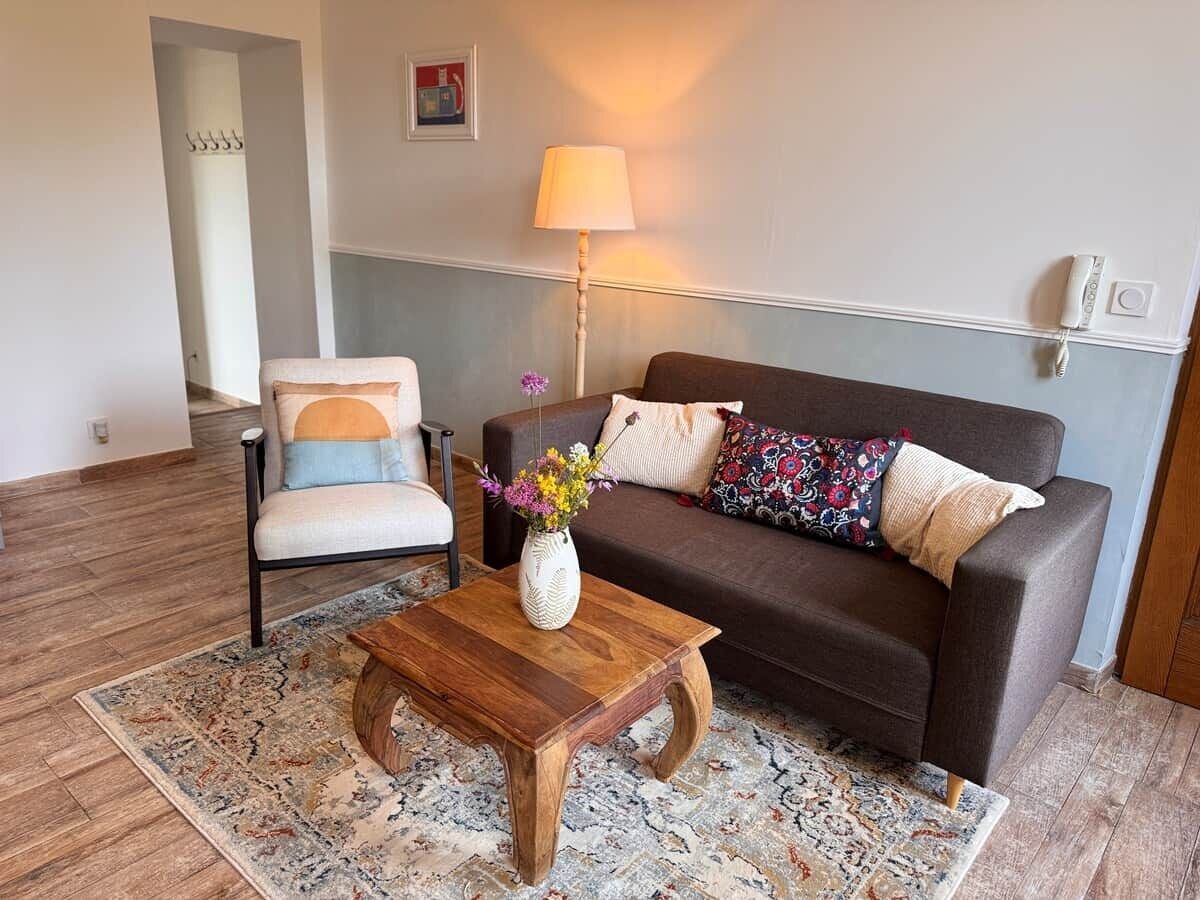 Ein Wohnzimmer mit Sofa, Sessel, Couchtisch und einer Lampe.