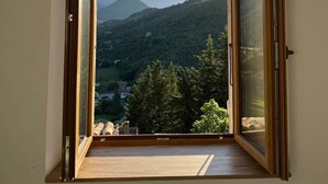 Une pièce dotée d’une grande fenêtre ouverte, qui offre une vue sur un paysage montagneux.