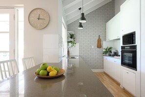 A kitchen with a granite countertop, white cabinets, a clock, and a bowl of fruit. - The Turtle's Nest in Safety Bay - Near the Beach (Safety Bay)