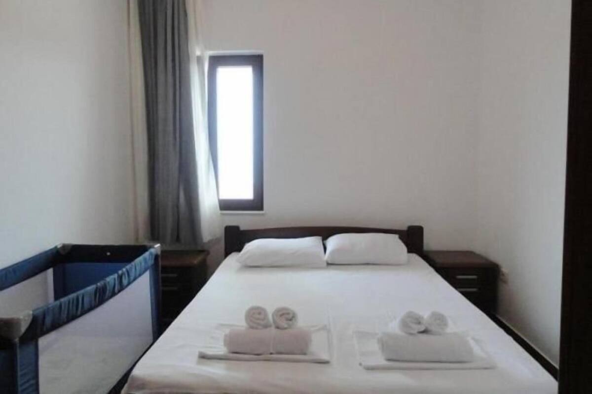 A hotel room with a single bed, a window, a curtain, and a small table with towels.