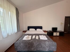 Un lit bien fait, recouvert d’une couvre-lit à motifs floraux, avec une paire de serviettes et un téléviseur posé sur un meuble à côté du lit.