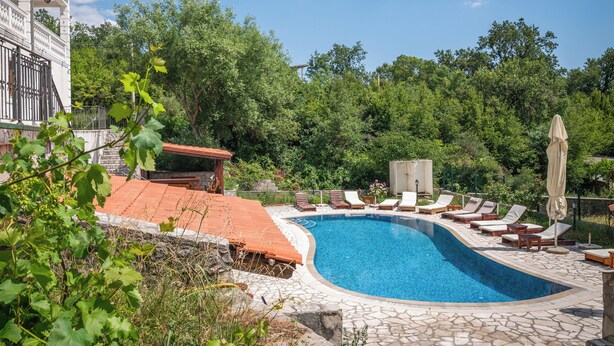 A swimming pool with lounge chairs and a stone deck. - Apartments Oasis (Markovići)