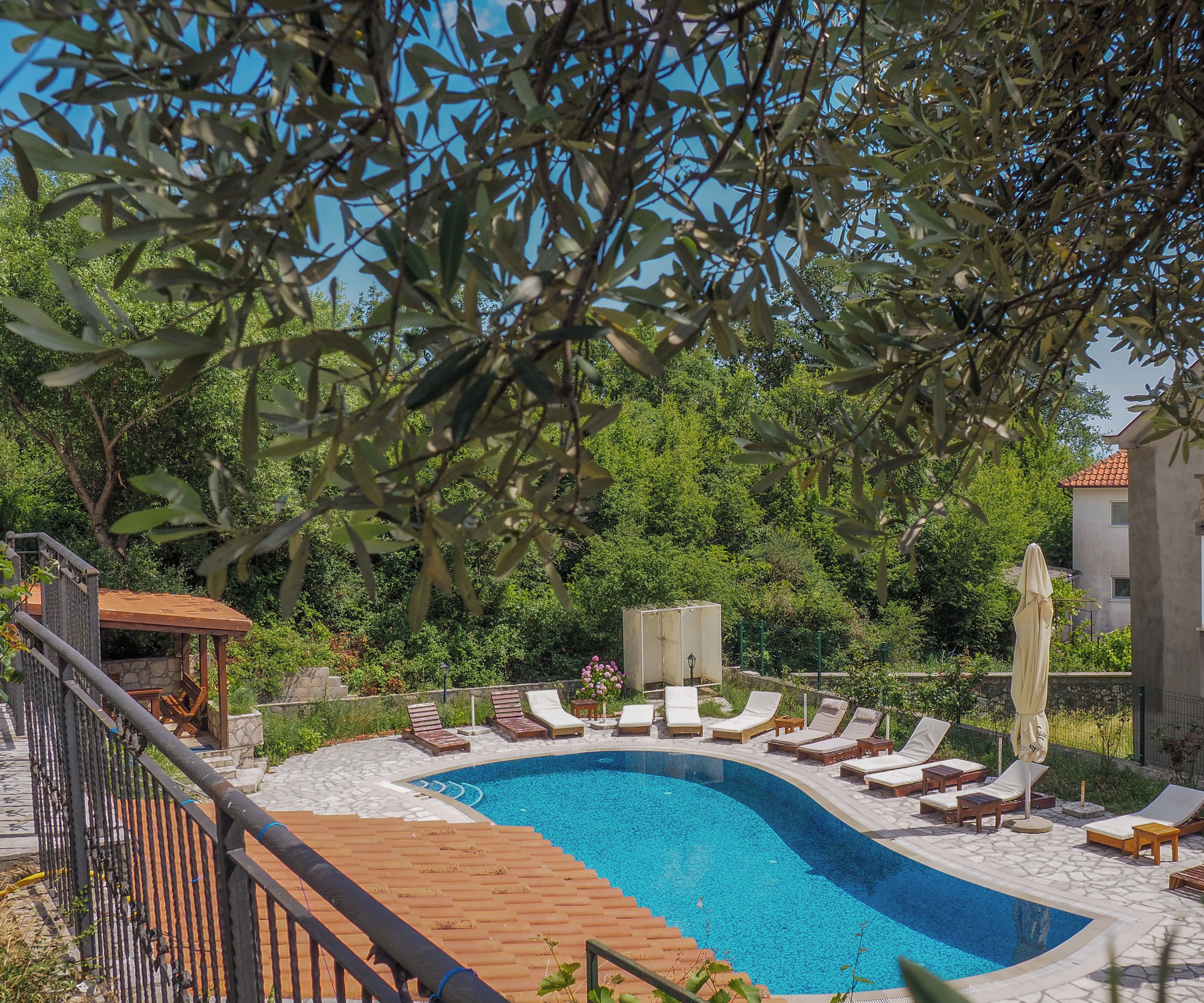 A swimming pool with lounge chairs, a wooden deck, and a stone pathway.