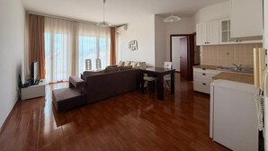 A modern living room with a sofa, dining table, and kitchen area. - Apartments Oasis (Markovići)