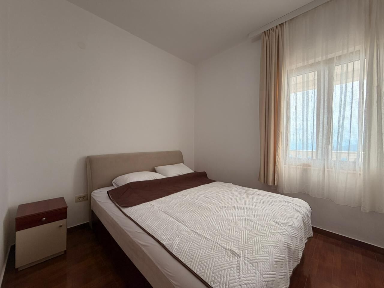 Une chambre à coucher avec un lit, une table de chevet et une fenêtre avec des rideaux.