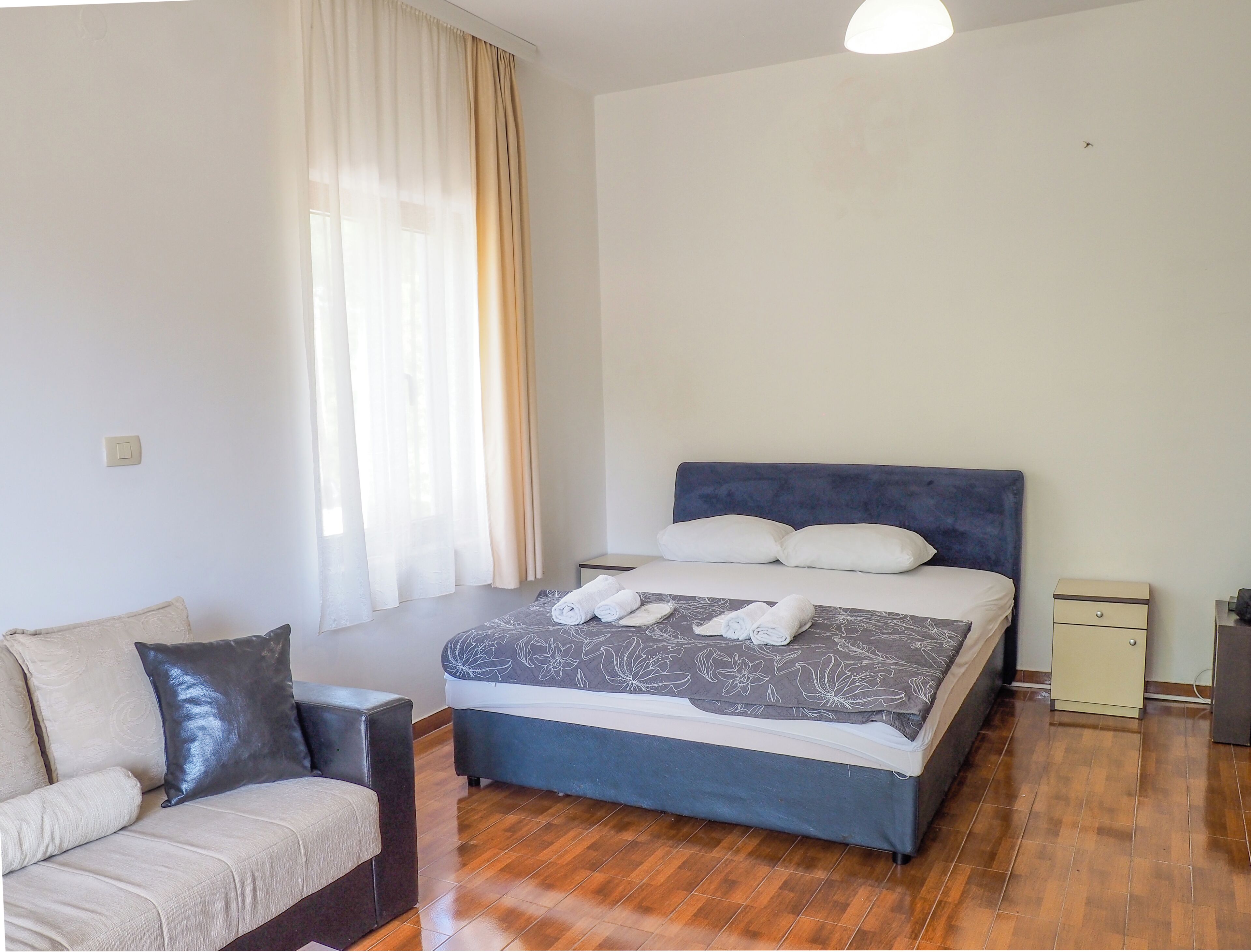 A bedroom with a bed, a chair, a nightstand, and a window with curtains.