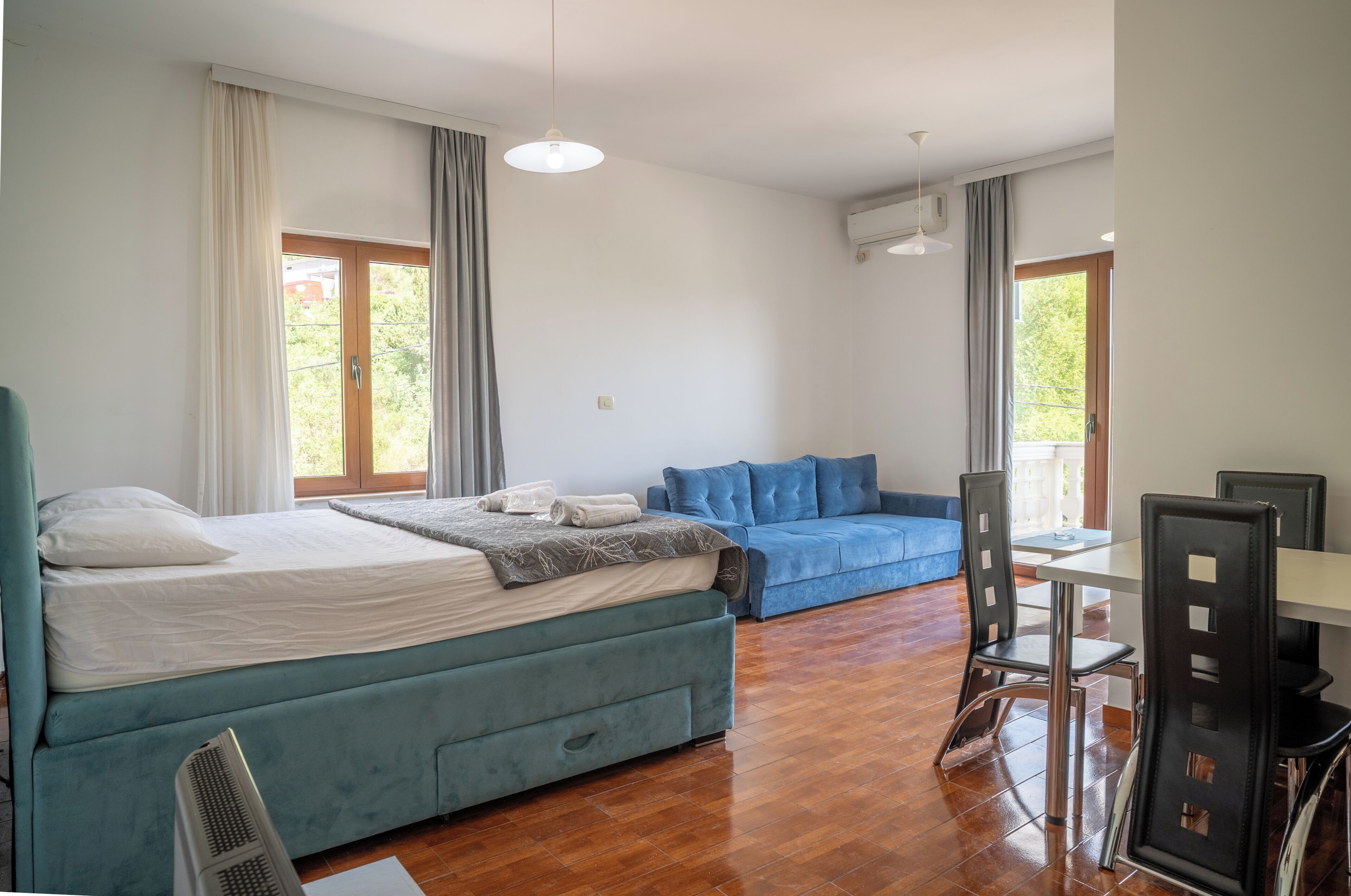 Un dormitorio con cama, sofá, mesa de comedor y sillas, y ventilador de techo.